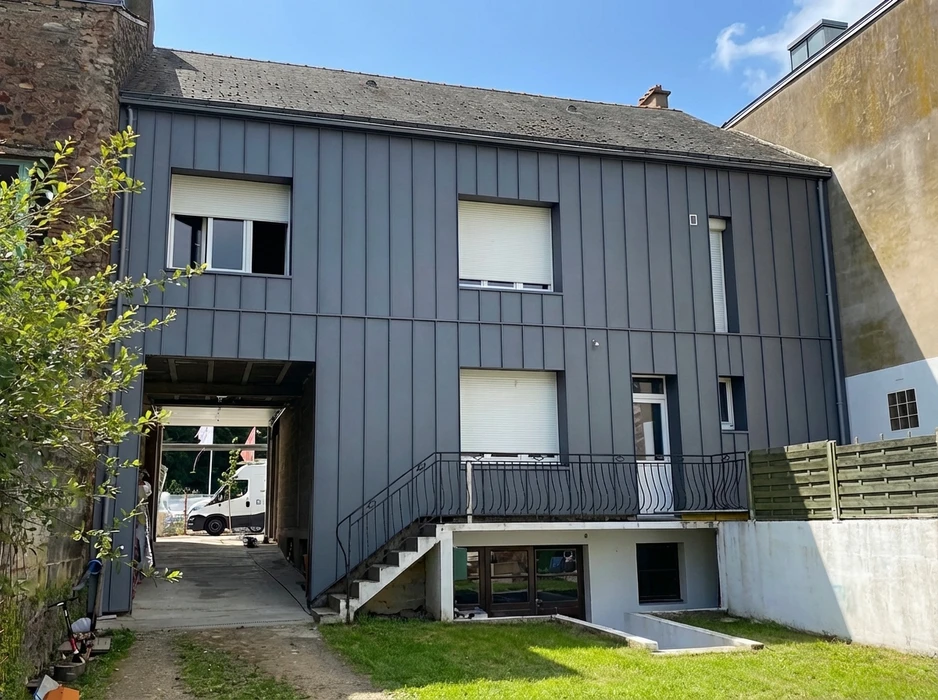 Façade rénovée d'un bâtiment résidentiel à bardage métallique vertical gris anthracite, pose en joint debout