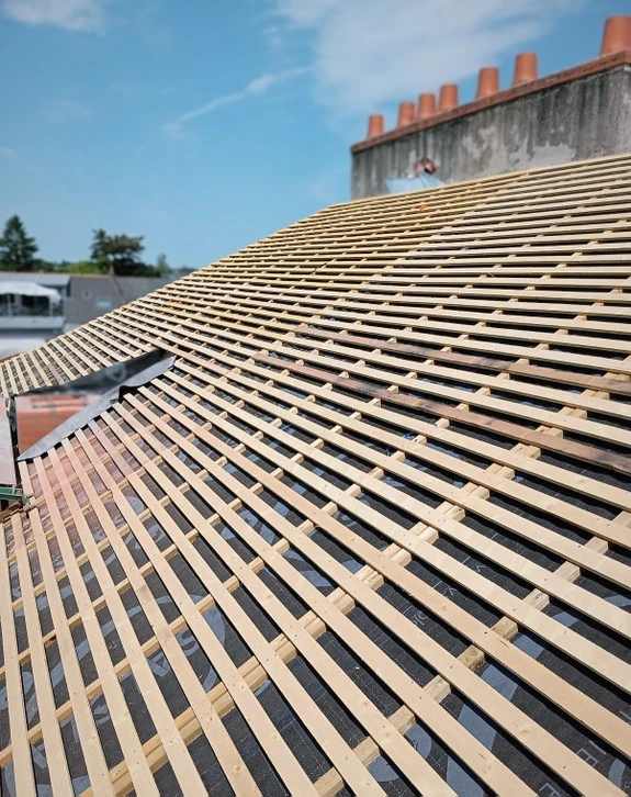 Gros plan sur une fenêtre mansardée sur le toit de la maison recouvert de bardeaux en céramique