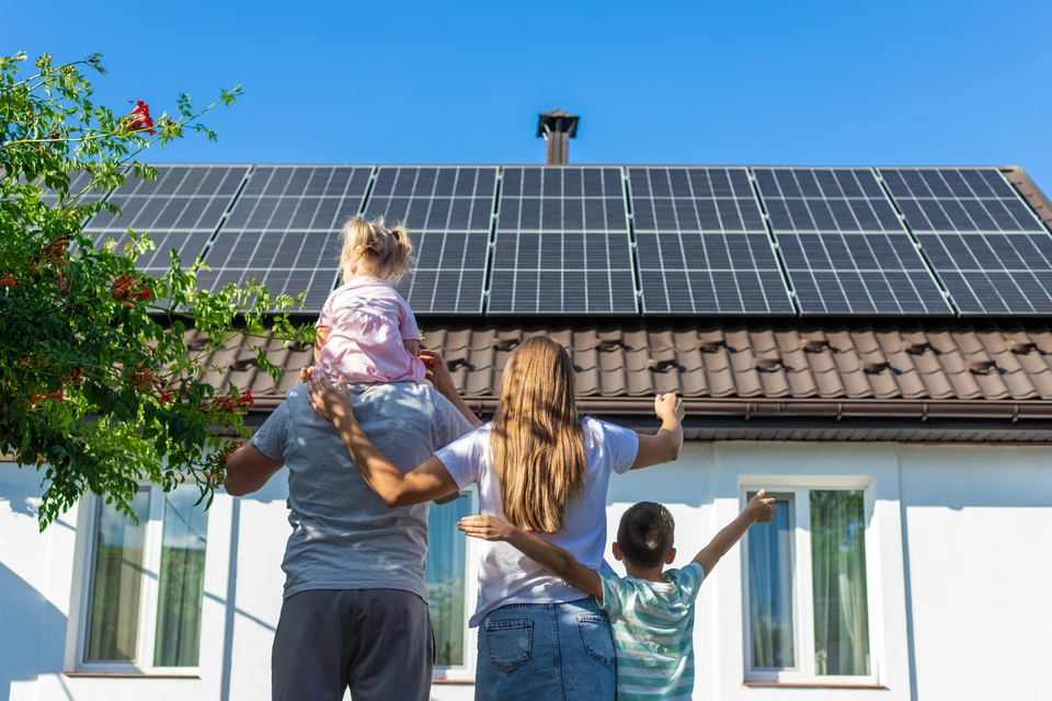 Toiture résidentielle équipée de panneaux solaires photovoltaïques sous ciel bleu dégagé, végétation verdoyante en arrière-plan