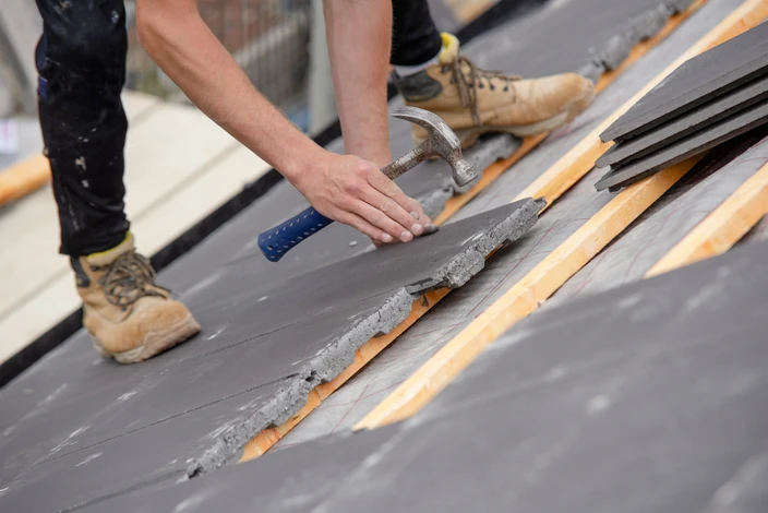 Toiture résidentielle extérieure avec couverture en ardoises grises sous ciel nuageux