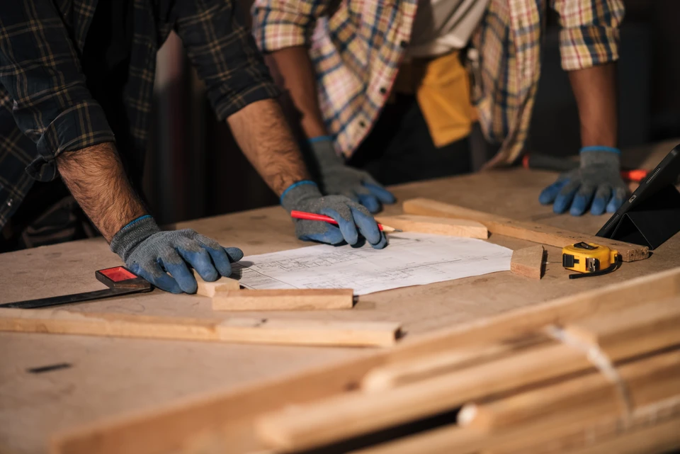 Atelier de menuiserie avec femme artisane souriante travaillant le bois à l'établi