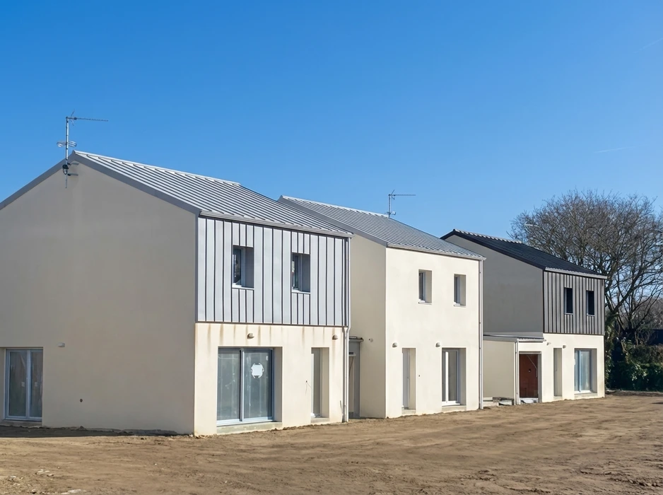 Vue aérienne d'un lotissement en construction, deux rangées de maisons individuelles en briques monomur rouge avec charpentes bois apparentes en cours de pose