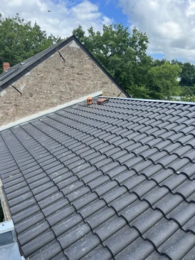 Couvreur professionnel installant des tuiles métalliques ondulées grises sur toiture résidentielle