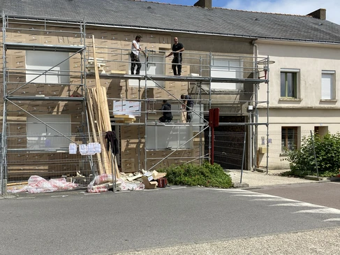 Un ouvrier en bâtiment installe un panneau isolant en polystyrène expansé sur un mur extérieur