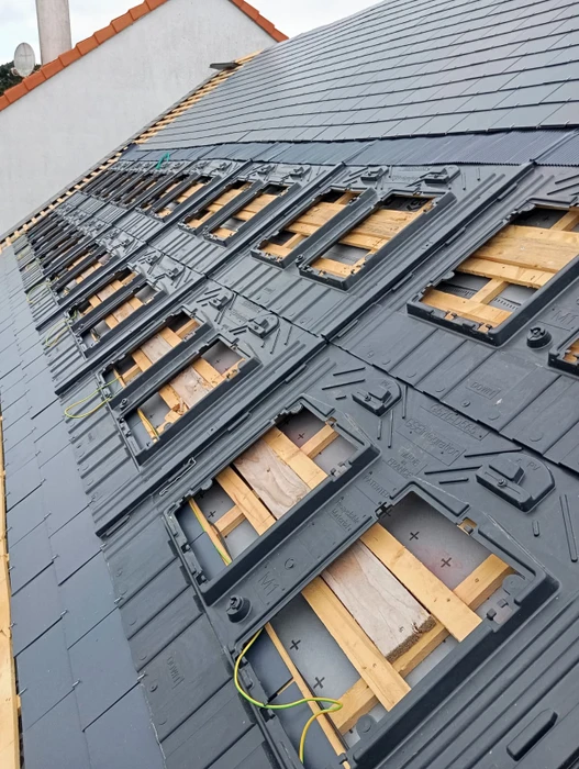 Toiture terrasse avec membrane EPDM grise, équipée de panneaux solaires photovoltaïques monocristallins noirs, montés sur ballasts d'inclinaison fixes