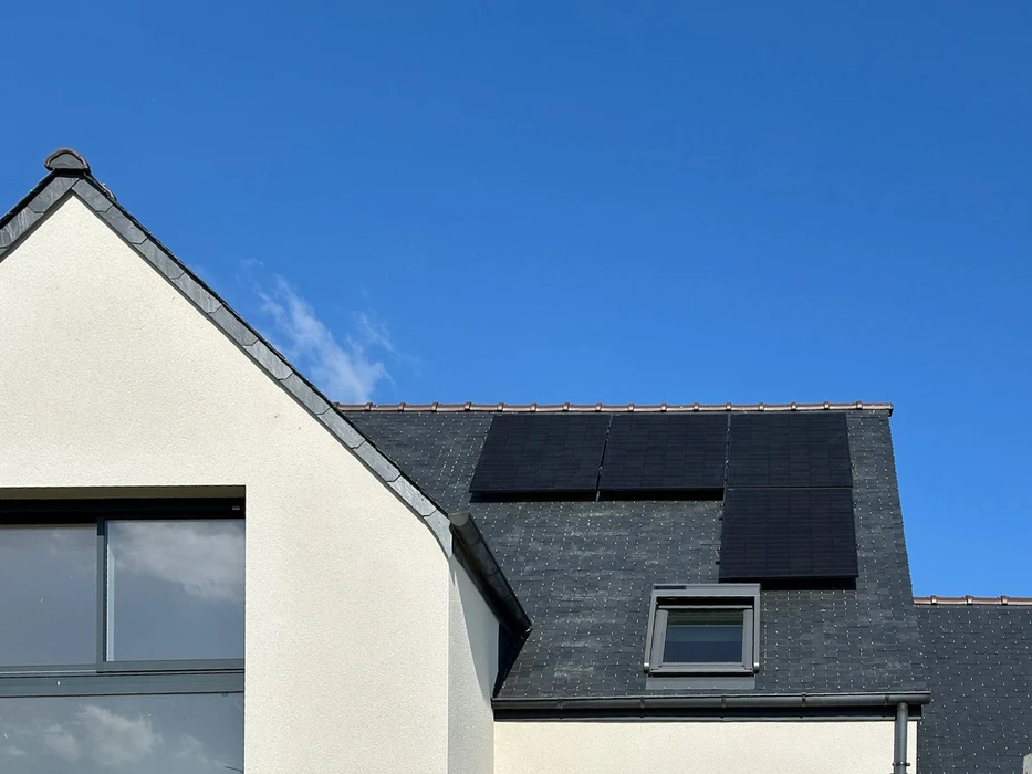 Toiture terrasse avec membrane EPDM grise, équipée de panneaux solaires photovoltaïques monocristallins noirs, montés sur ballasts d'inclinaison fixes