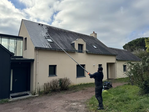 Couvreur effectuant un démoussage et entretien sur toiture en tuiles