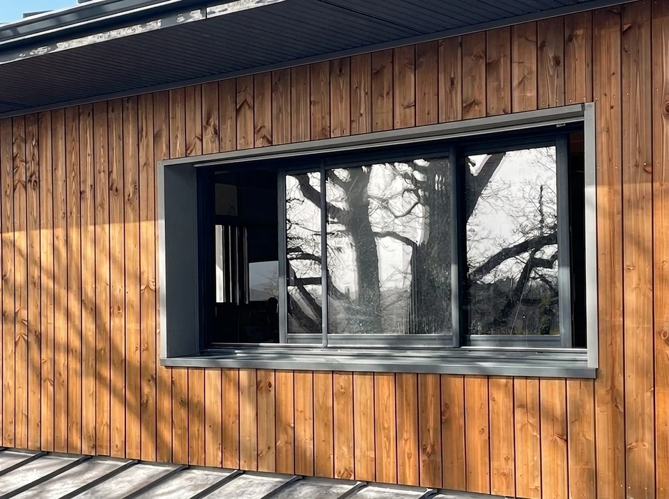 Façade moderne d'immeuble de bureaux avec bardage métallique bleu-gris à joints marqués